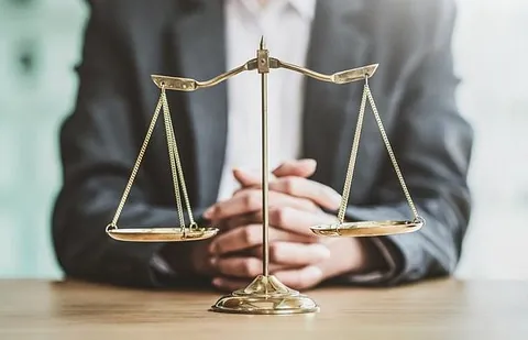 Goldene Waage der Gerechtigkeit auf einem Holztisch vor einem Rechtsanwalt in Delmenhorst, Symbol für Recht und Fairness.