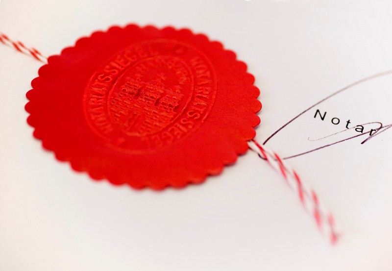Rotes Notarsiegel auf beglaubigter Urkunde mit Unterschrift von einem Notar in Delmenhorst.